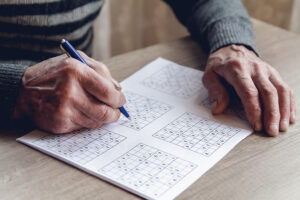 Elderly man solves sudoku or a crossword puzzle